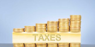 Stacked coins with "TAXES" on block beneath.