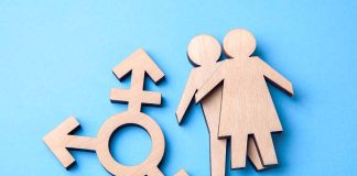 Wooden transgender symbol and couple figures on blue background