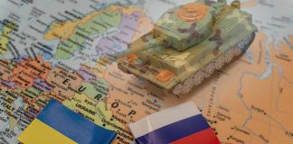 Toy tank on map with Ukraine and Russia flags.
