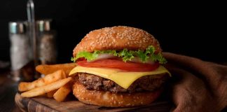 Cheeseburger with fries on a wooden board.