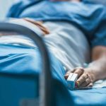 Person lying in hospital bed with monitor attached