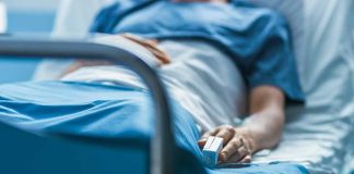 Person lying in hospital bed with monitor attached