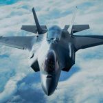 Jet flying above clouds, viewed from front.