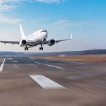 Airplane taking off from runway against blue sky