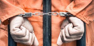 Hands cuffed behind bars in prison uniform