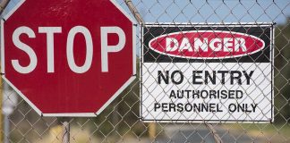 Stop and Danger signs on a chain-link fence.
