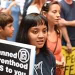People at a protest holding signs against Planned Parenthood