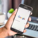 Hand holding smartphone with Google search page