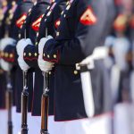 Military officers standing in formation holding rifles.