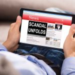 Person reading tablet with headline Scandal Unfolds.