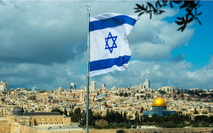 1065289910 featured image Israeli flag flying over Jerusalem cityscape and Dome.