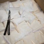 Bags of white powder with scissors in cardboard box