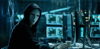 Person wearing mask and hoodie at computer desk