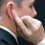Man wearing an earpiece touching his ear
