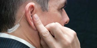 Man wearing an earpiece touching his ear