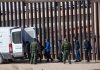 People near border fence with border patrol van