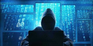 Person in hoodie using a laptop with digital code