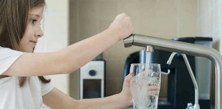 Girl filling glass with water from kitchen faucet