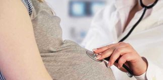 Doctor uses stethoscope on pregnant woman's belly