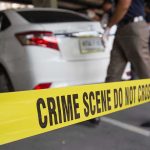Crime scene tape blocking off white sedan