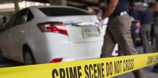 Crime scene tape blocking off white sedan