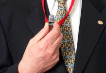 Person holding a whistle on a red lanyard