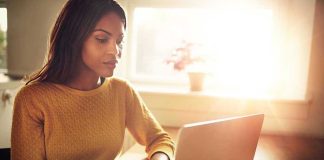 Woman using a laptop while holding a mug