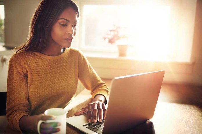Woman using a laptop while holding a mug