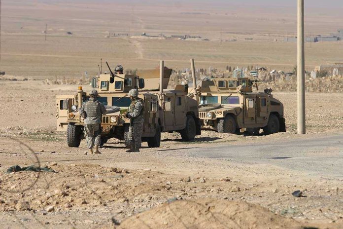 76580419 Soldiers standing near armored vehicles in desert terrain