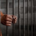 Hands gripping prison cell bars