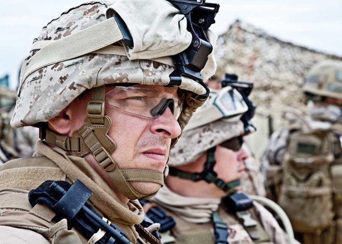 shutterstock_147102638.jpg Two soldiers in military gear looking serious in an outdoor setting