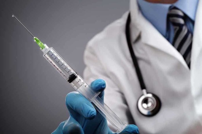 shutterstock_149167064.jpg A doctor holding a syringe with a stethoscope around their neck