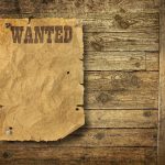 A vintage wanted poster pinned to a wooden wall