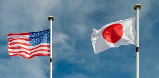 USA and Japan flags flying on flagpoles.