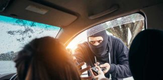 Masked person robbing a woman inside a car.