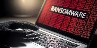 Gloved hand on laptop with ransomware screen.