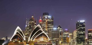 Sydney Opera House at night with city skyline.