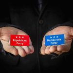Hands holding Republican and Democratic Party cards.