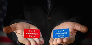 Hands holding Republican and Democratic Party cards.
