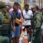 Federal Raids EXPOSE Massive Trafficking Empire Border patrol agents inspecting group of individuals in line.