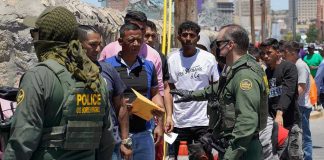 Border patrol agents inspecting group of individuals in line.
