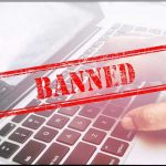 Outrage Erupts After Roblox Bans Pedophile Hunter Red Banned stamp over a laptop keyboard.