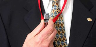 Person holding a whistle on a red lanyard.