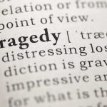 Close-up of the word 'Tragedy' in a dictionary with its definition