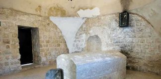 Interior of a historical site featuring a stone tomb and ancient walls