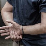 SHOCKING ICE Blunder—Citizens ARRESTED, Rights Shredded! Person in handcuffs with hands behind back.