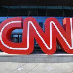 Large red CNN sign outside building entrance.