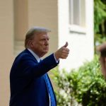 Trump TAKEN To Hospital – Critical Health Concern! Man in suit giving thumbs up.