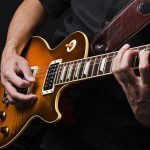 Hands playing an electric guitar.