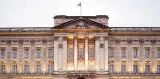 Front view of Buckingham Palace with illuminated facade and British flag